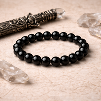lack beaded bracelet on a textured surface with decorative knife and crystals.
