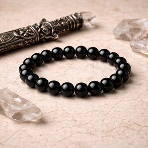lack beaded bracelet on a textured surface with decorative knife and crystals.