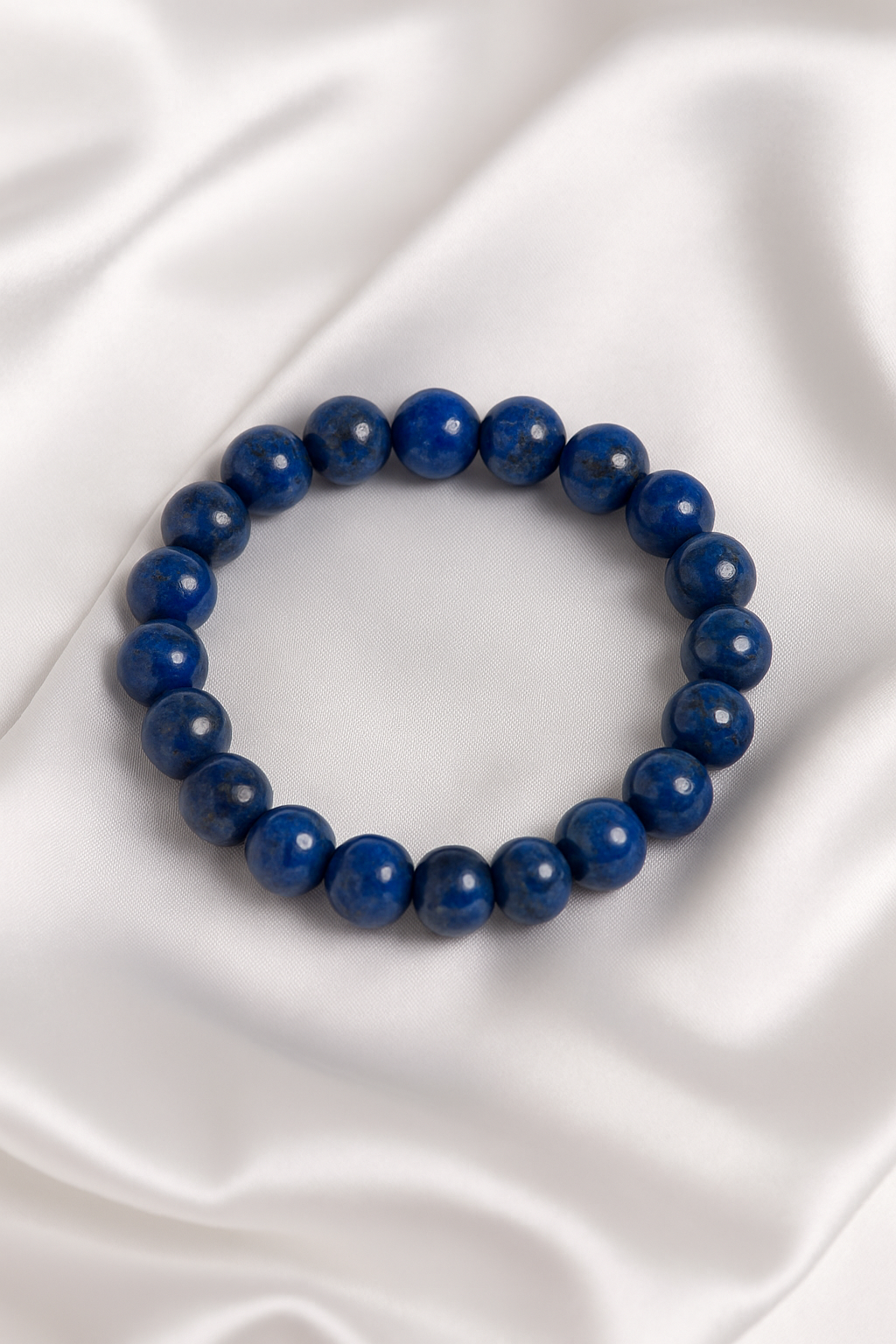 Blue beaded bracelet on a white satin background