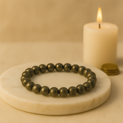 Bronze beaded bracelet on a marble surface with a candle in the background