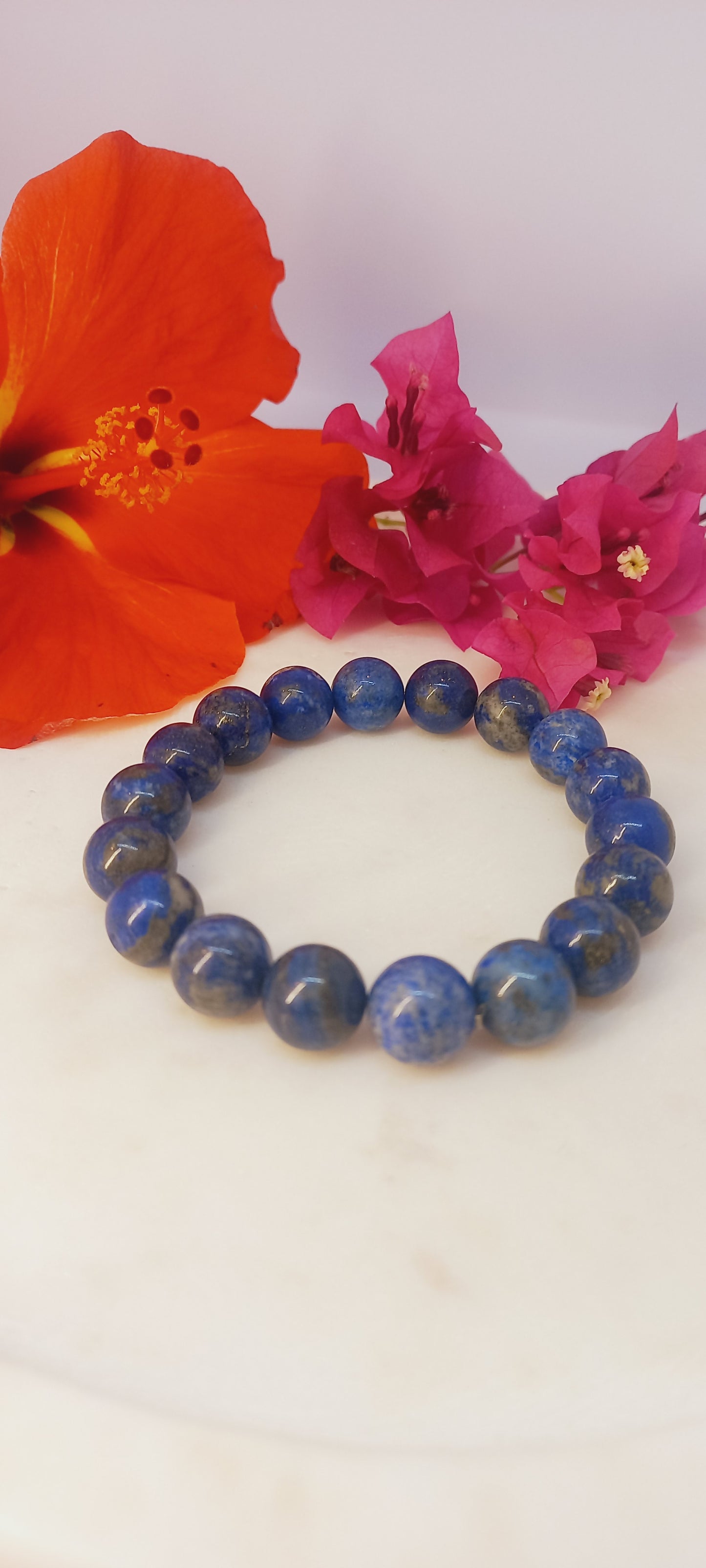Blue beaded bracelet with pink and red flowers on a white background