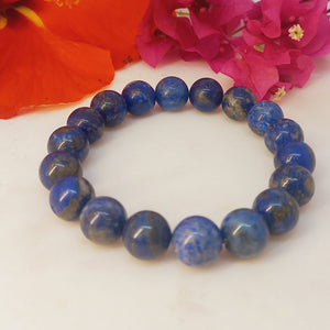 Blue beaded bracelet with pink and red flowers on a white background