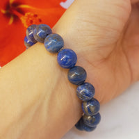 Blue beaded bracelet on a wrist with a red flower in the background